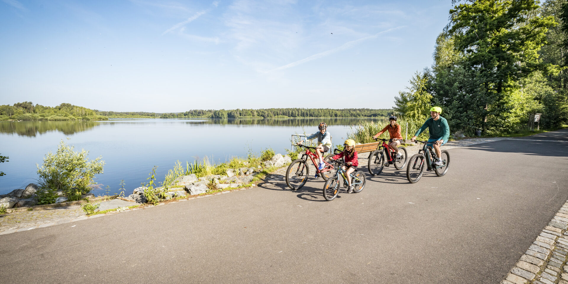 Familie beim Radfahren am Rußweiher; im Hintergrund Rußweiher